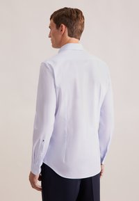 Lichtblauwe, lange mouwen shirt met een fijn patroon, standaard kraag en knoopmanchetten. Heeft een gebogen zoom en gestikt logo-detail nabij de manchet.