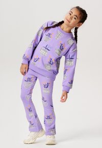 Lila tröja och byxor-set med blommönster och tekannor. Mjuk tyg, ribbad mudd och slim-fit design. Skor i pastellfärger.