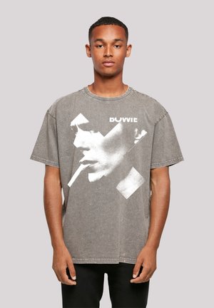 Graues, oversized T-Shirt mit einem Grafikdesign eines Gesichts und dem Text "BOWIE." Der Stoff sieht gewaschen aus und verleiht einen vintage Look.