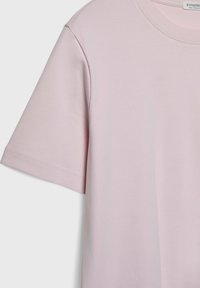 Lyserød kortærmet T-shirt lavet af blød bomuld, med en simpel rund halsudskæring og glat tekstur. Enkel, minimalistisk design.