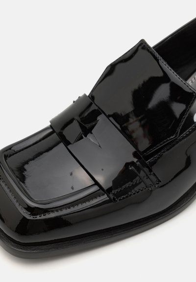 Black patent leather loafers with a square toe, featuring a horizontal strap accent and stitching details along the edges.