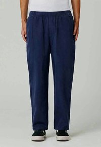 Navy blue cotton pants with an elastic waistband, featuring side pockets and a relaxed, straight-leg fit. Smooth texture with no visible patterns.