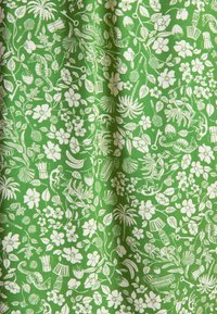 Grüner Stoff mit einem weißen floralen und botanischen Muster, das verschiedene Blumen, Blätter und kleine Pflanzen im gesamten Design zeigt.