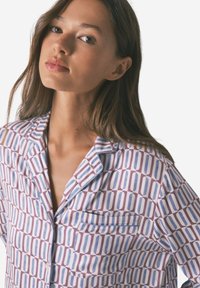 Koszula piżamowa z długim rękawem uszyta z lekkiego materiału, z geometrycznym wzorem niebieskich i bordowych prostokątów, z kieszonką i kontrastowym wykończeniem.