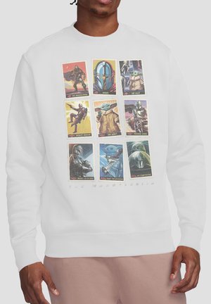 Person wearing white sweatshirt featuring nine colored Mandalorian-themed collectible card designs arranged in a 3x3 grid on the front.