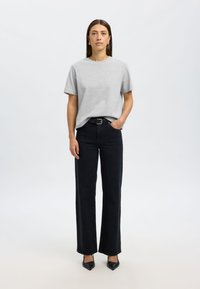 Sivá tričko s krátkym rukávom, čierne vysoký pás široké nohavice, doplnené čiernymi lodičkami s špicatou špičkou, elegantný strih a hladká textúra.
