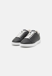 Black leather sneakers with white rubber soles. Features include white laces and a logo on the tongue, with a smooth texture and rounded shape.