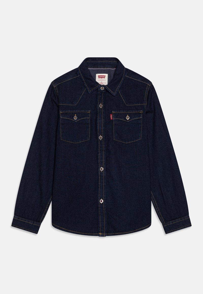 Chemise en denim bleu foncé à manches longues avec deux poches poitrine boutonnées, un col et des surpiqûres jaunes visibles.