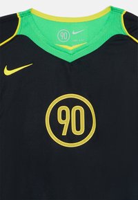 Jersey desportivo preto com realces verdes, apresentando um decote em V, textura em malha e um gráfico circular amarelo com "90" no centro. Logotipo da Nike presente.
