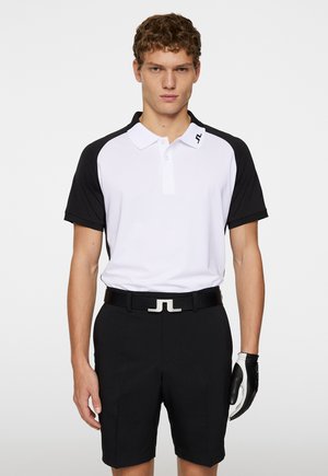 Men's polo shirt in white with black short sleeves, textured fabric, paired with black shorts. Black belt features a distinctive logo buckle.