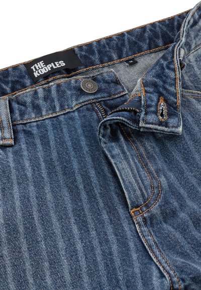 Jeans dżinsowe w ciemnym niebieskim kolorze z efektem sprania i kontrastowym przeszyciem. Posiadają zamek błyskawiczny, zapięcie na guzik i etykietę na talii z logo.