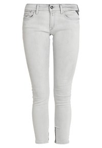 Ljusgrå skinny jeans i denim med en slät yta, som har framfickor, dragkedja och små sprund vid anklarna.