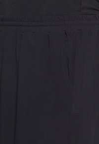 Tecido leve e preto com uma superfície texturizada. Apresenta um cós elástico e bolsos laterais, design pregueado para maior volume.