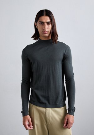 Dark green long-sleeve sweater with a high neck and fitted design, made from a smooth material. The sleeves are slightly tapered at the cuffs.