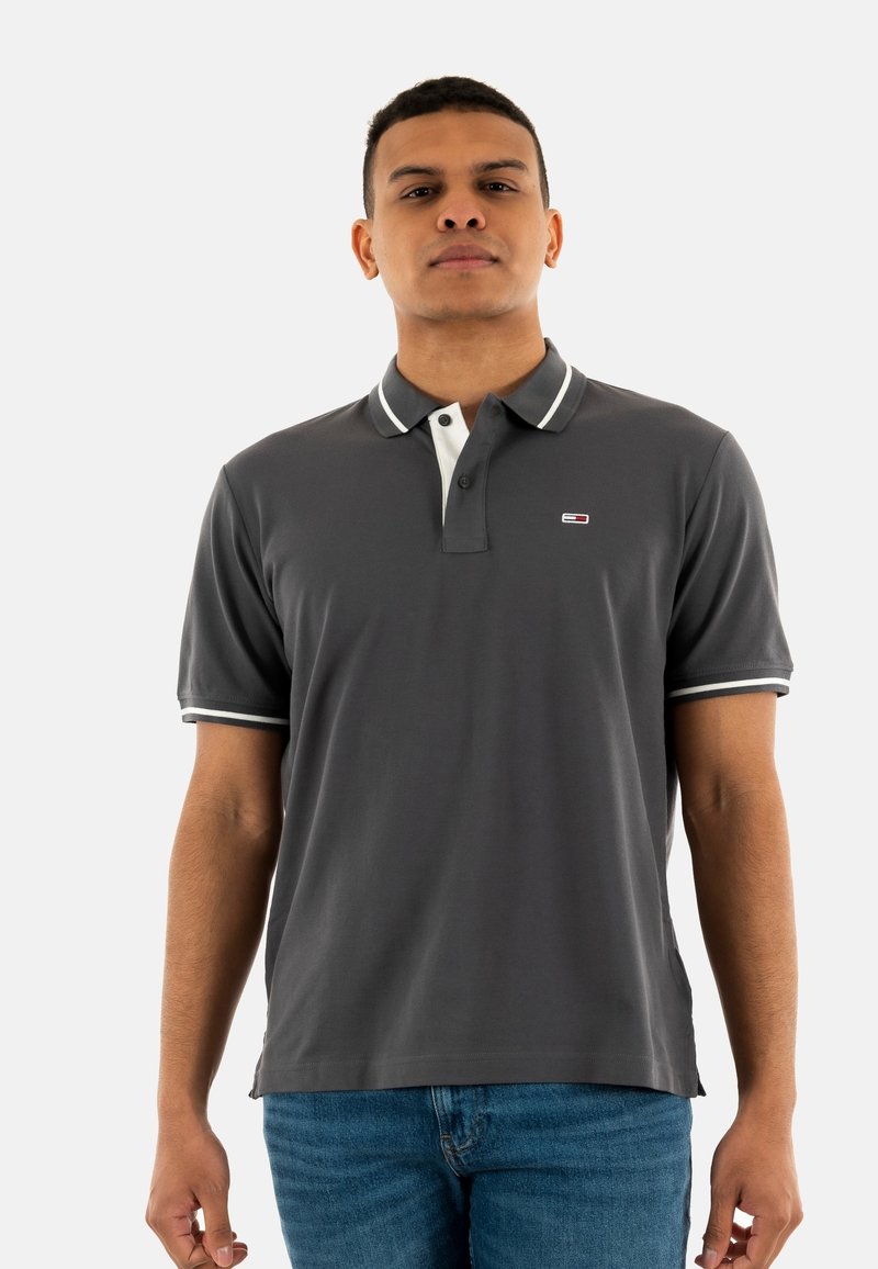 Camisa polo gris con cuello blanco y acentos a rayas; mangas cortas, confeccionada en una tela suave, con un pequeño logo en el pecho.