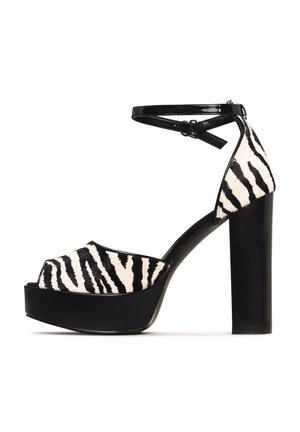 Zwart-witte open teen platform sandalen met zebra patroon, gepatenteerde enkelband en een chunky zwart hak. Textuur bovenwerk met glanzende accenten.