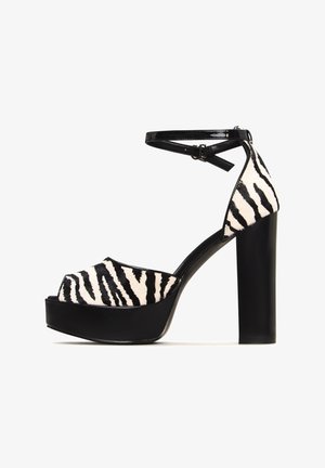 Schwarz-weiße Peeptoe-Plateausandaletten mit Zebra-Muster, patentierter Knöchelriemen und einem massiven schwarzen Absatz. Strukturierte Oberseite mit glänzenden Akzenten.