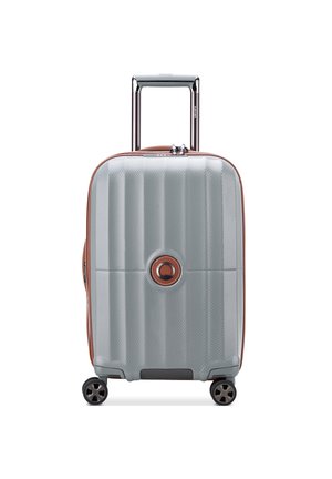 Hard-shell carry-on suitcase in light gray with horizontal ridges, brown accents, a circular logo, and four rotating wheels for mobility.