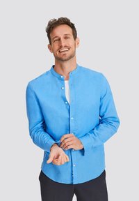 Light blue button-up shirt with a stand-up collar, long sleeves, and a relaxed fit. Made from a smooth fabric with subtle texture.