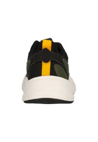 Baskets noires et vertes avec un dessus texturé, un tirant au talon jaune, et une semelle intermédiaire blanche avec une semelle extérieure noire.