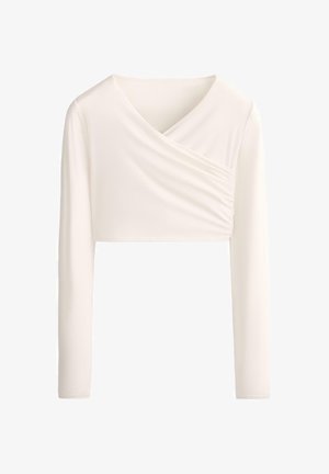 Top corto a maniche lunghe color crema con scollo asimmetrico drappeggiato e dettaglio di tessuto raccolto sul lato destro anteriore.