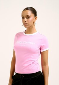 T-shirt rose à manches courtes avec un col et des poignets de manches blancs contrastants. Présente le logo "Juicy Couture" en blanc. Design doux et ajusté.