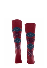 Rote knielange Socken mit einem Rautenmuster in Blau und Bordeaux, verziert mit weißen Nähten. Die Socken sind aufrecht präsentiert.