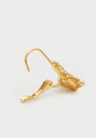 Náušnice na klip v zlatém tónu s jemnými detaily, hladkým povrchem, zakřiveným háčkem a malými kamínky podél okraje.