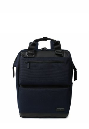 Sac à dos carré bleu foncé avec deux grandes poches zippées, poignées noires et une petite étiquette de marque en bas à droite.
