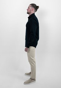Zwarte langemouwen shirt, beige chinos en beige instappers. Classic fit, knoopsluiting ontwerp en textuurstof zichtbaar.
