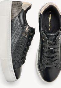 Sneakers neri con pelle texturizzata, suola in gomma bianca, chiusura con zip e parte anteriore con lacci. Dettagli metallici e un design a motivi delicati. Taglia 37.