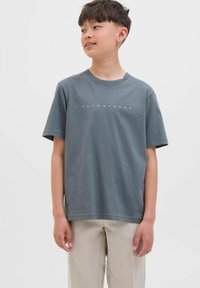 Camiseta de algodón gris de manga corta, con un escote redondo y "JACK & JONES" impreso en texto blanco en el pecho. Textura suave.