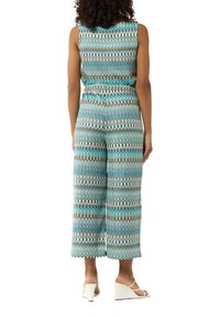 Jumpsuit multicolore avec des motifs ondulés en teal, marron et crème. Design sans manches, coupe évasée et taille élastique pour le confort.