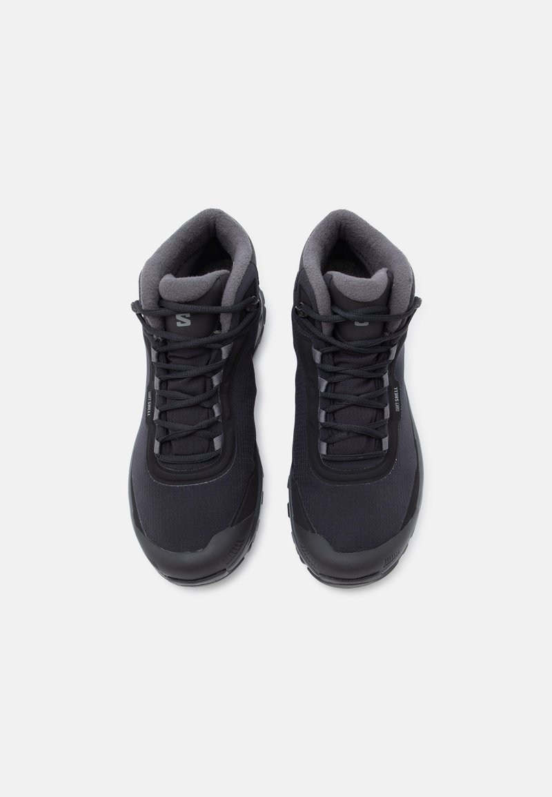 Sorte vandrestøvler med et tekstureret stofoverdel, polstret grå krave og gummisåler. Har sorte snørebånd og diskret branding på siden.