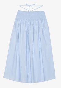 Jupe en coton bleu clair avec taille smockée, silhouette fluide, larges plis et fines bretelles à nouer au dos pour un ajustement adaptable.