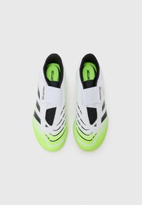 Zapatillas deportivas blancas con una banda negra, acentos verdes y múltiples perforaciones para transpirabilidad. Presentan un diseño sin cordones con una correa de Velcro.