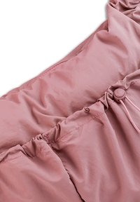 Tissu léger rose avec un design froncé et des accents élastiques. Comprend un bouton et un cordon de serrage ajustable pour un maintien sécurisé.