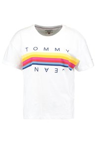 Vit bomullströja med ett horisontellt flerfärgat randigt mönster i nyanser av gult, rosa och blått, samt texten "TOMMY".