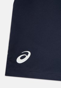 Marina atletiska shorts tillverkade av ett glatt tyg, med en vit logotyp i nedre vänstra hörnet och ren sömnad längs fållen.