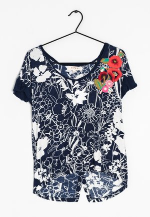 Navyblå kortærmet skjorte med et hvidt blomstermønster og broderede røde og grønne blomster ved halsudskæringen. Blødt stof, afslappet pasform.