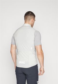 Maillot de cyclisme à manches courtes gris clair en matériau extensible. Doté d'une poche zippée à l'arrière et d'un logo dans le bas du dos.