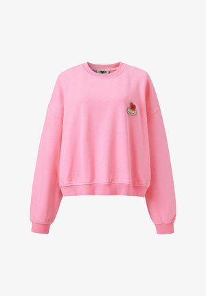 Sweat-shirt rose à col rond avec manches longues et petite écusson en forme de cœur rouge sur le côté gauche de la poitrine.