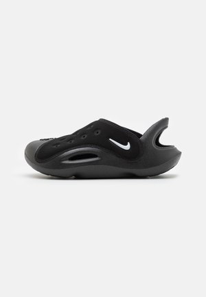 Chaussure slip-on noire Nike avec des trous de ventilation, logo Nike swoosh blanc, et une bride de talon surélevée sur fond blanc uni.