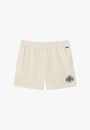 Pantalones cortos de malla color crema con cinturilla elástica. Presenta un logo verde de Lacoste y el texto "París" en la parte inferior derecha.