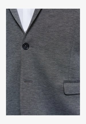 Harmaa bleiseri, joka on valmistettu teksturoidusta kankaasta. Siinä on yksi musta nappi, rintatasku ja viistetyt lapel-kaa.