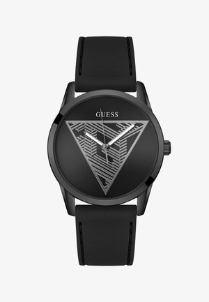 Montre Guess noire avec un cadran au design géométrique triangulaire, aiguilles des heures et des minutes en argent, bracelet en silicone noir et aiguille des secondes en argent.