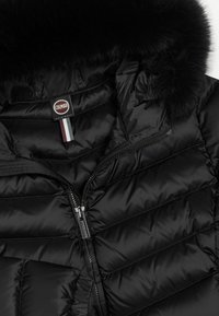 Schwarze Pufferjacke mit abnehmbarem Kunstfellkragen, ausgestattet mit einem Reißverschluss und diagonalem Steppmuster. Das Markenlabel ist innen sichtbar.