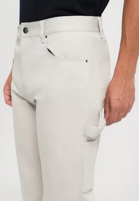 Lichtbeige cargobroek met een aansluitend ontwerp, vervaardigd van een katoenmix. Voorzien van voorzakken en een zijcargozak. Soepele textuur.