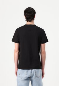 Schwarzes Baumwoll-T-Shirt mit kurzen Ärmeln und rundem Ausschnitt, das ein einfaches Design und einen regulären Schnitt aufweist. Der Stoff wirkt weich und glatt.