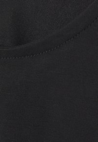 Svart tyg med en glatt yta, som har en rund halsringning och en ribbad nederkant. Materialet verkar elastiskt och åtsittande.